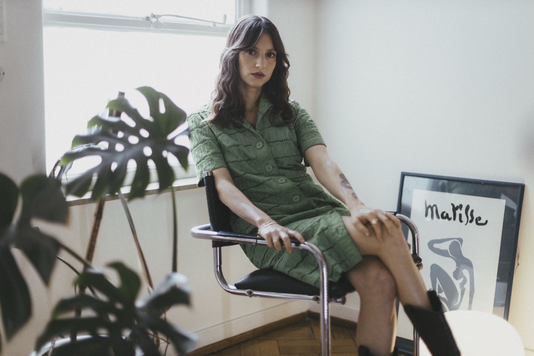 Agostina Faedda con vestido verde, sentada junto a una ventana con plantas
