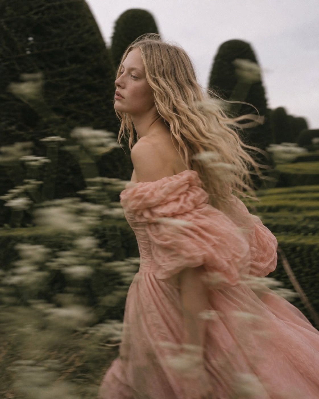 Mujer rubia con vestido rosa en un jardín